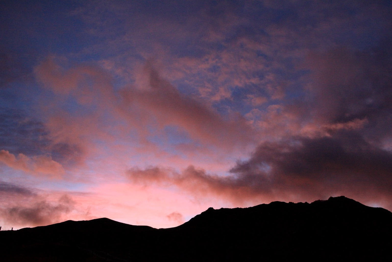 Mountain ridge silhouetted beneath pink evening clouds
